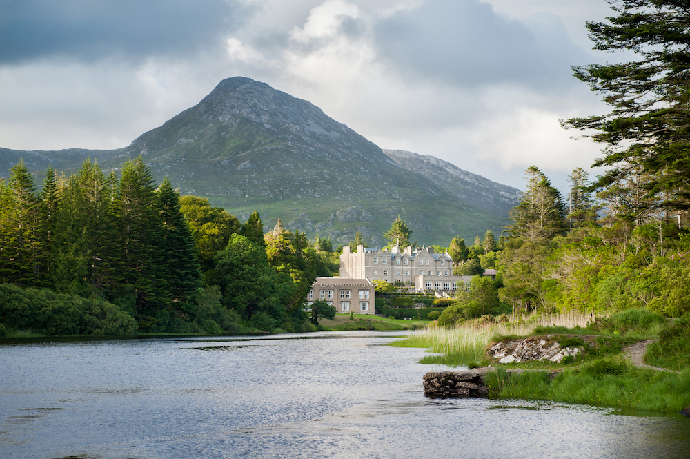 places to travel in September from the UAE: view of Ballynahinch Castle, Ireland, on a lake surrounded by mountains